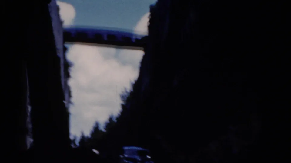 Shadowed car interior in the 1975 Florida footage, with a bright blue-and-white sky visible through the window opening.