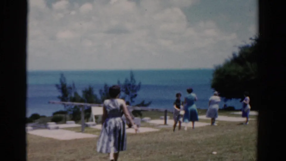 1975 Florida home-movie frame showing women in summer clothes walking near a railing at a coastal overlook.