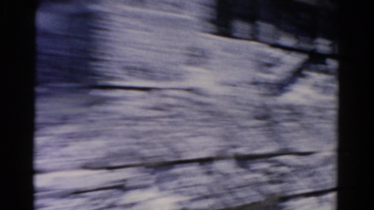 Motion-blurred close view of a pale wall or building surface beside the road.