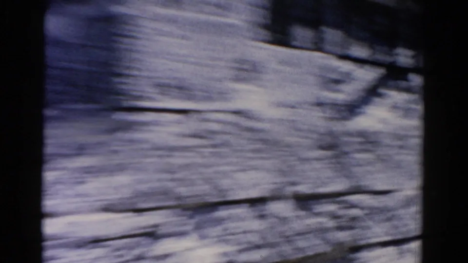 1975 Florida 8mm frame passing a pale waterfront wall or building surface, heavily blurred by the moving vehicle.