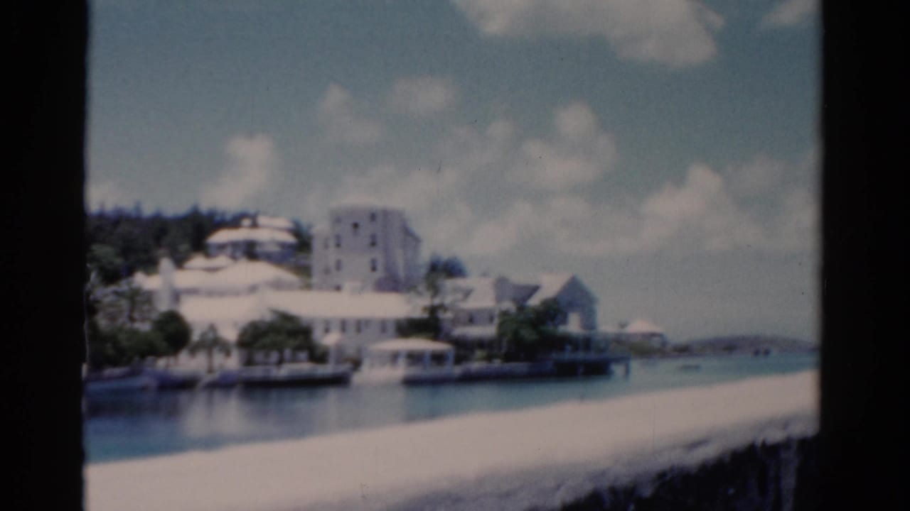 Similar waterfront view with white buildings, trees, and water in the foreground.