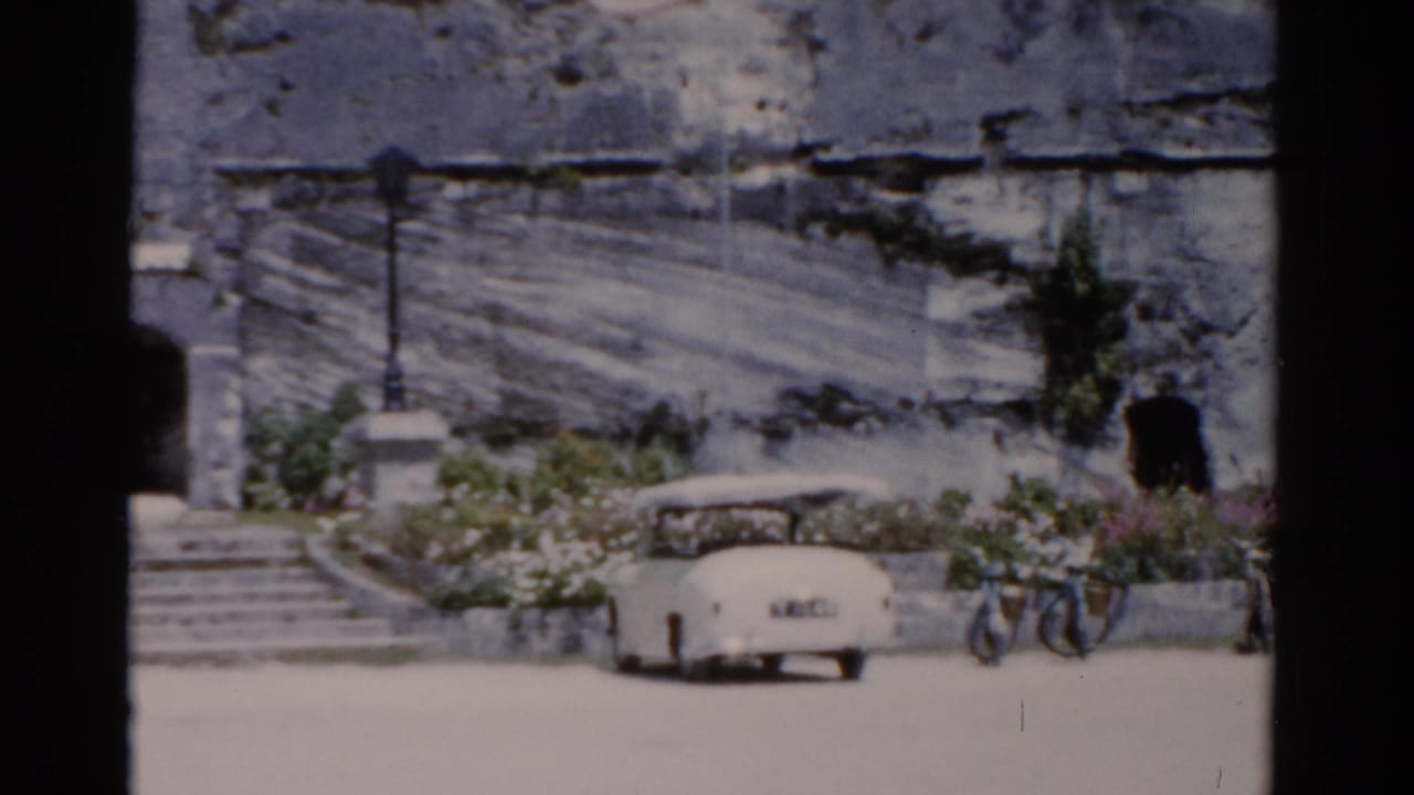 White convertible parked near stone steps and a dark arched entrance.