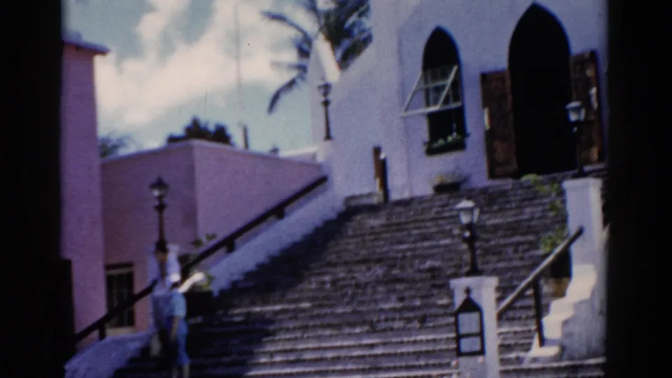 1975 Florida home-movie frame showing a white church above a broad stairway, with a distant person on the steps for scale.