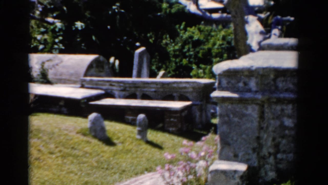 Florida 1975 8mm frame showing above-ground stone tombs, small grave markers, grass, and shaded trees.