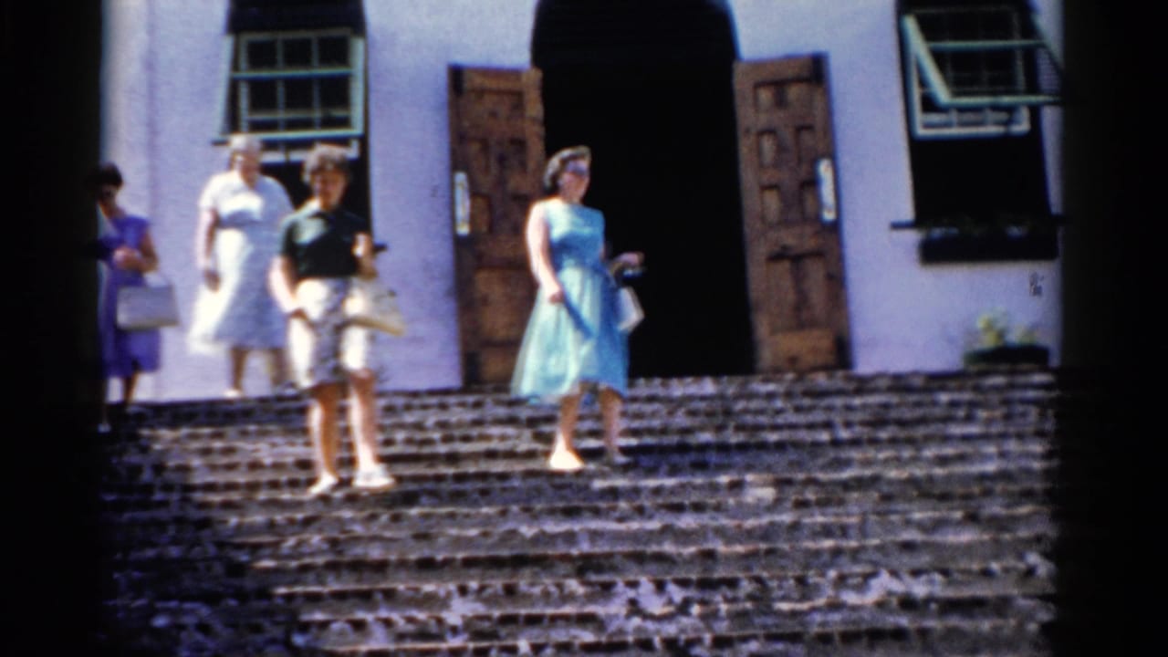 Women walk down a broad staircase from a white building with open doors and windows.