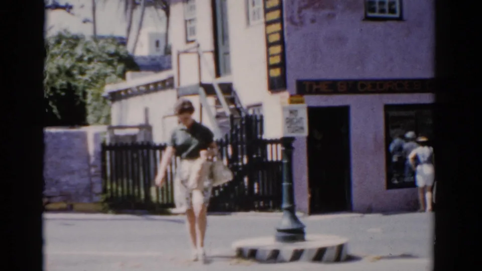 1975 Florida home-movie frame showing a woman carrying a light bag while walking in front of The St Georges Gift Shop.