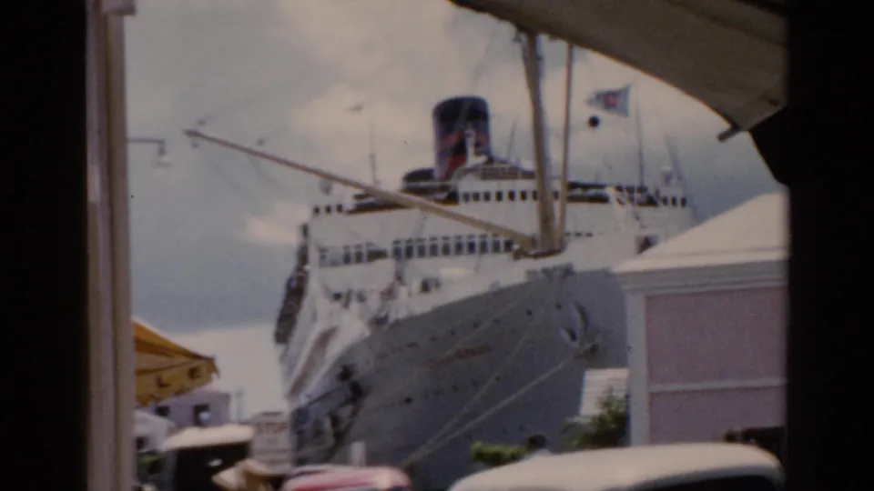 Large passenger ship at a Florida harbor in 1975, seen through a dark foreground frame with waterfront structures nearby.
