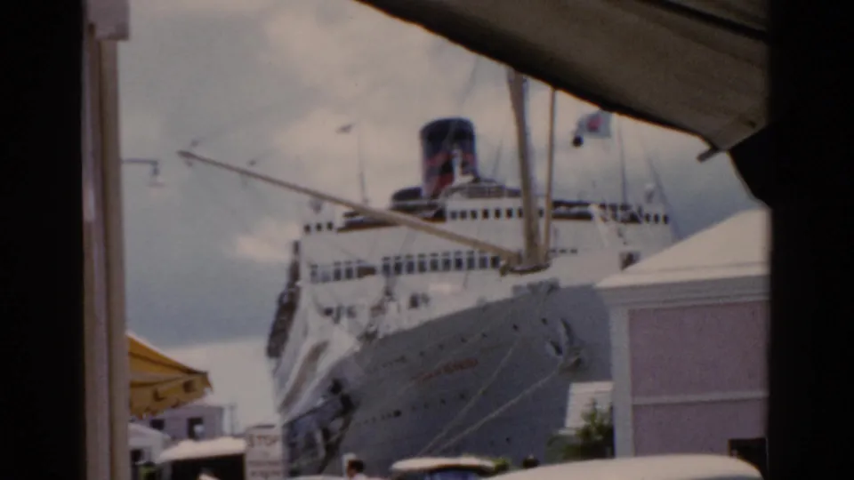Soft 8mm frame of a docked cruise ship in a Florida harbor, with older cars and waterfront structures visible below.