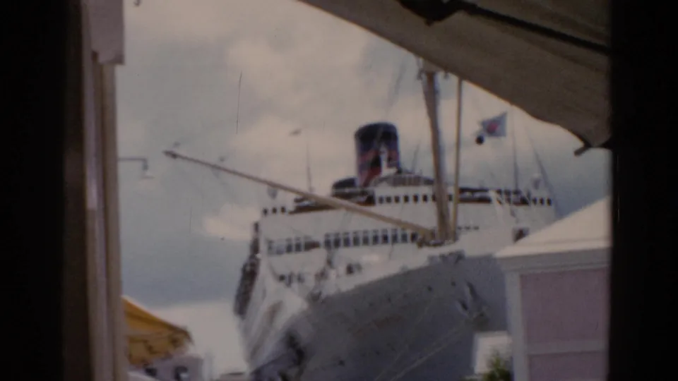 1975 Florida home-movie view of a cruise ship at the dock, partially obscured by a shaded foreground frame and nearby building.