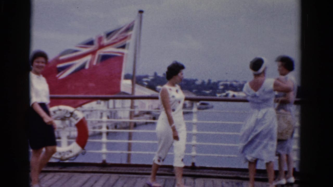 1975 Florida home-movie frame with several adult women on a ship deck, including one near a red life ring and others talking by the rail.