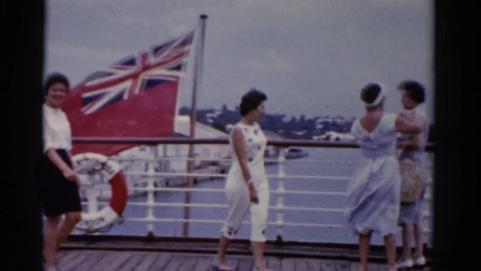 1975 Florida home-movie frame with several adult women on a ship deck, including one near a red life ring and others talking by the rail.