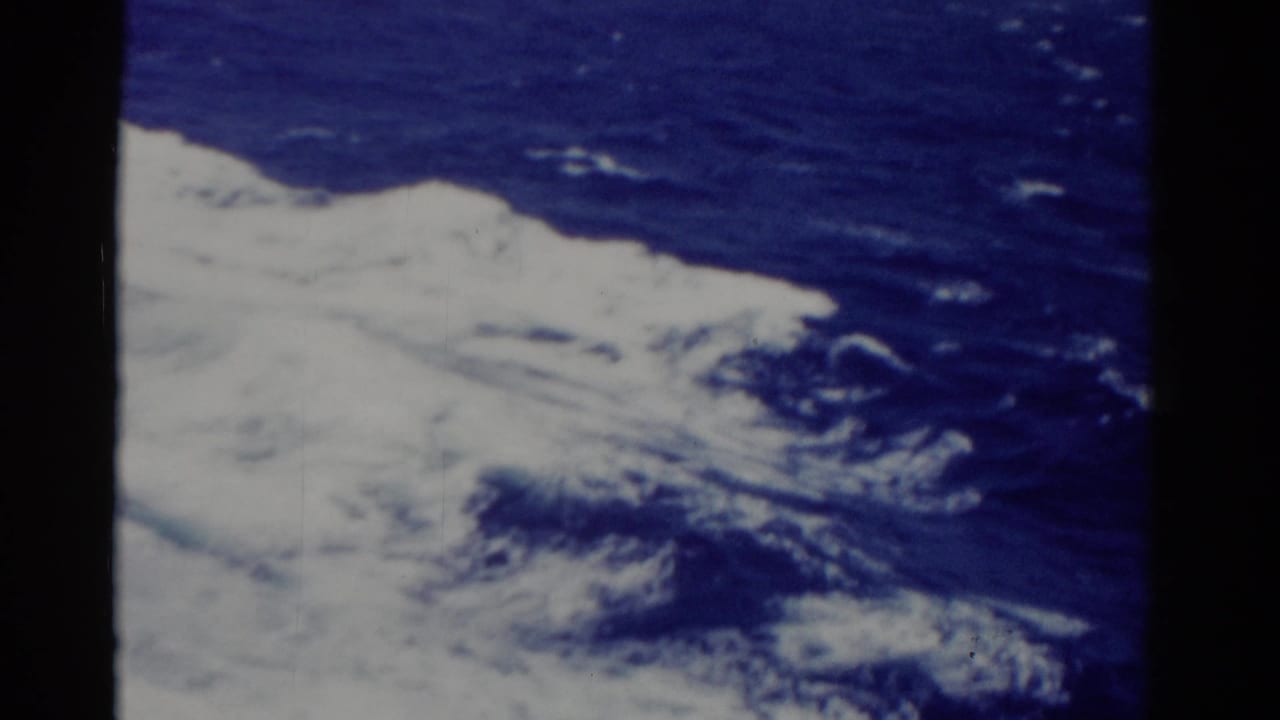 1975 Florida 8mm frame of churning white water across a dark blue ocean surface, framed by film gate edges.