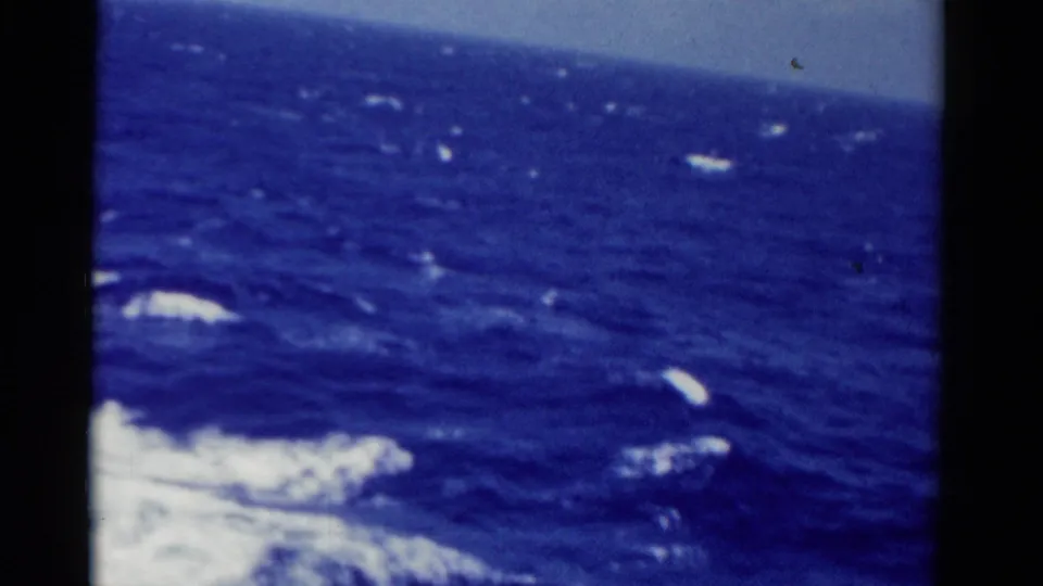 1975 Florida 8mm frame with open blue water, scattered whitecaps, and boat wake entering from the lower left.