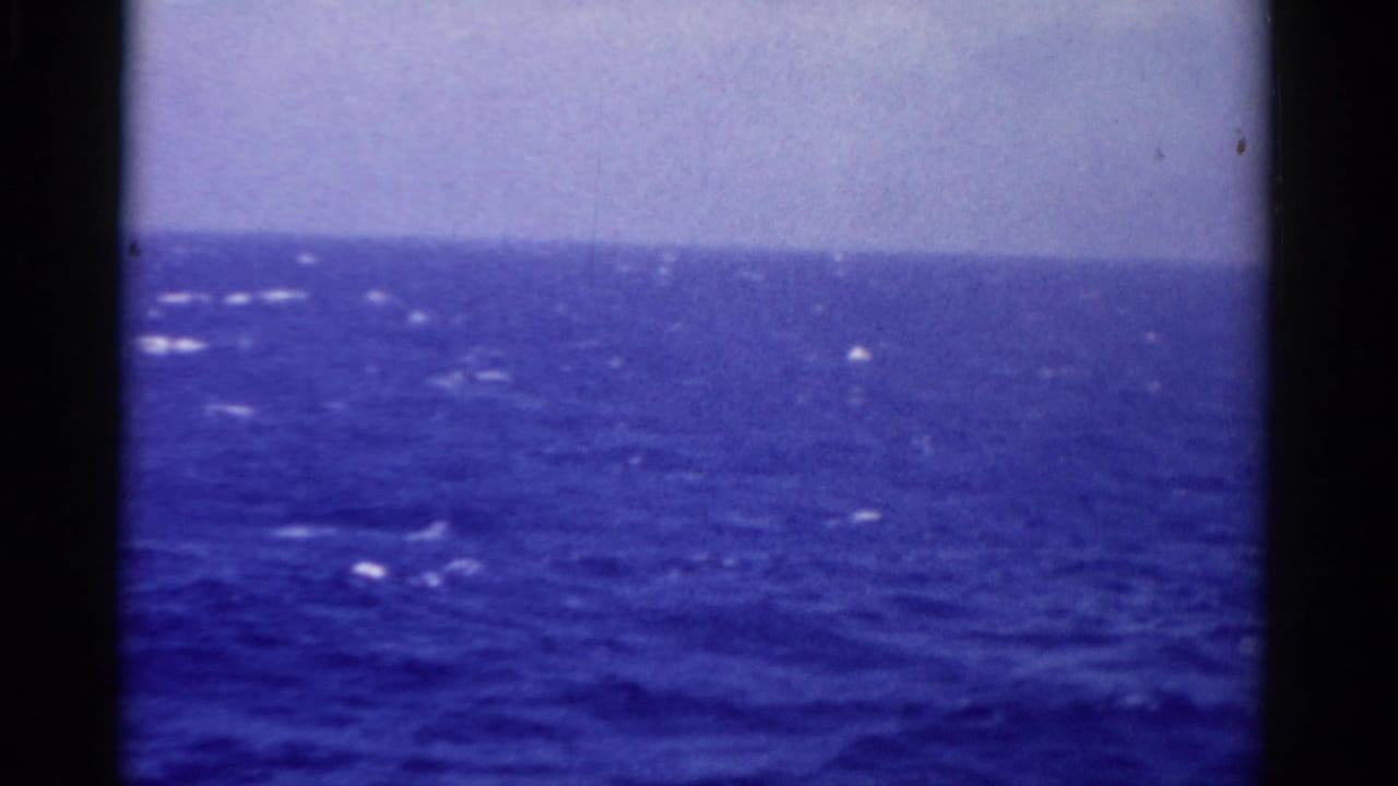 1975 Florida home-movie frame of open ocean from a moving vessel, with pale sky, whitecaps, and film gate edges.