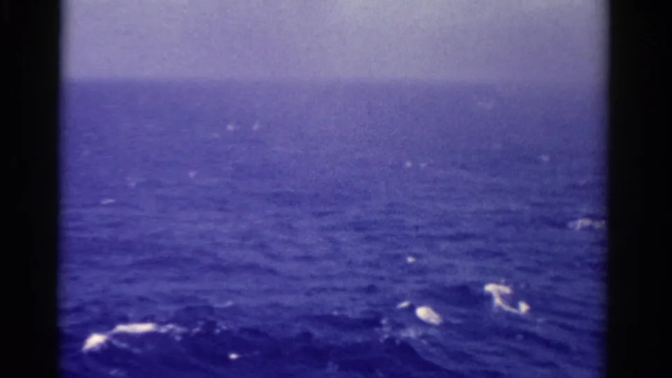 1975 Florida 8mm open-water frame showing blue sea, pale horizon, and brighter foam near the bottom edge.