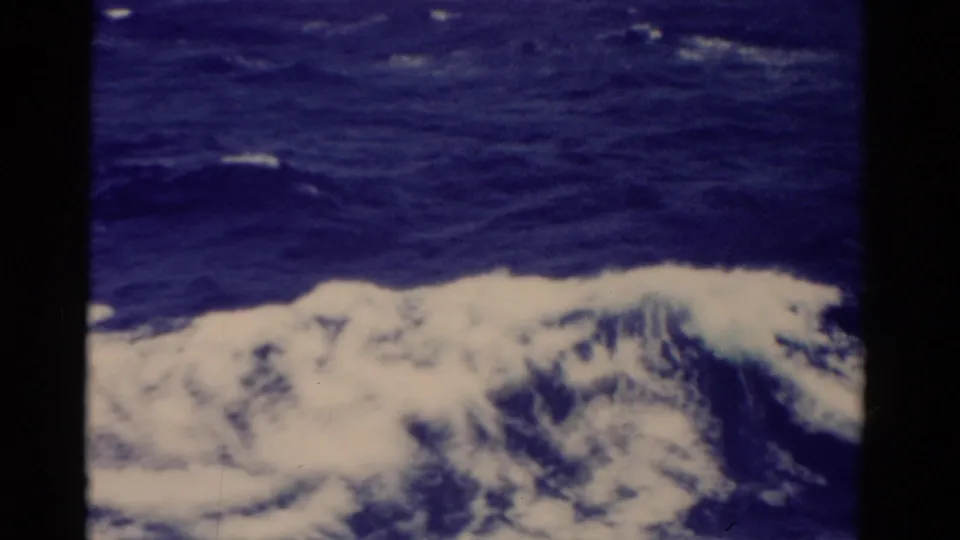 1975 Florida-linked 8mm frame showing foamy wake beside a ship and rough open water beyond.