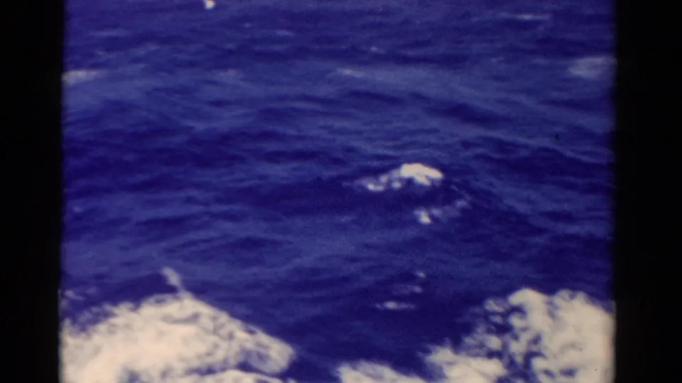 1975 Florida-linked 8mm view of rolling blue water, white foam, and a dark shipboard obstruction in frame.