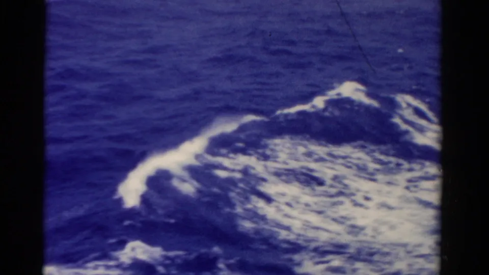 1975 8mm Florida ocean footage showing a broad white wave crest and wake pattern below blue water.