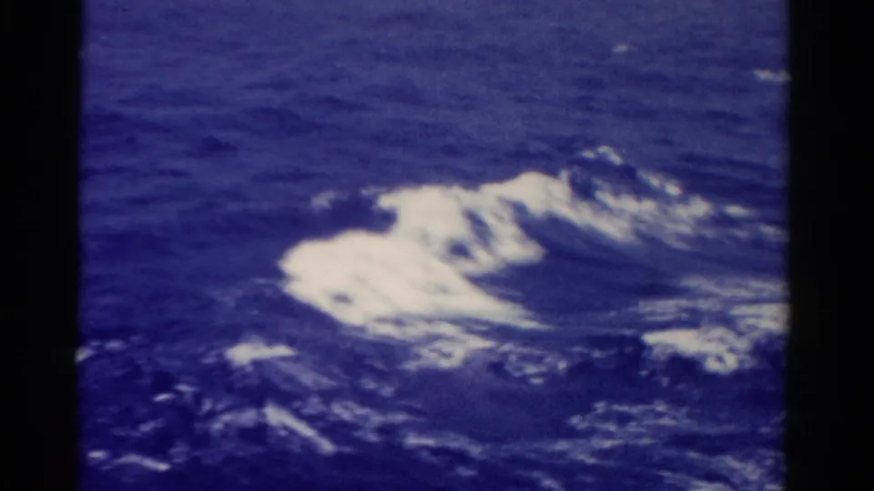 1975 8mm Florida sea surface with white foam streaks and churning wake on dark blue water.