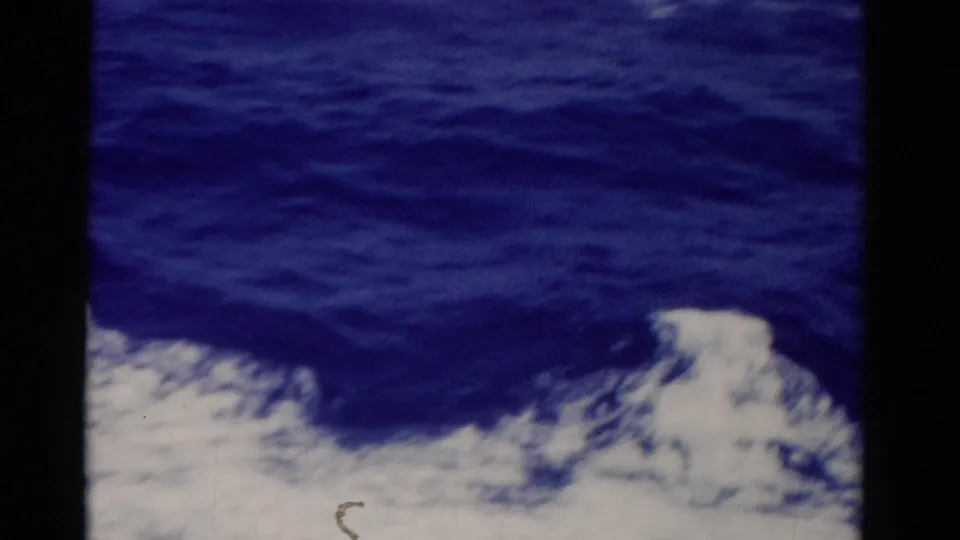 1975 Florida 8mm frame showing blue sea and white foam viewed from a moving vessel, with soft focus and dark film edges.