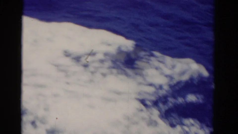 1975 Florida 8mm frame with a broad foamy wake pushing across blue water, seen from a passenger-like moving viewpoint.