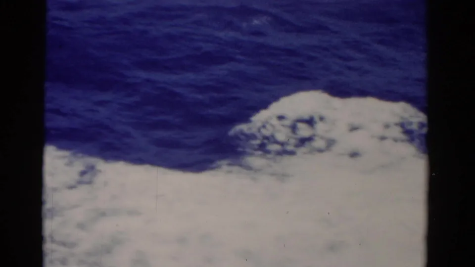 1975 Florida 8mm ocean frame showing white sea foam at the lower edge and textured blue water above, with archival film borders.