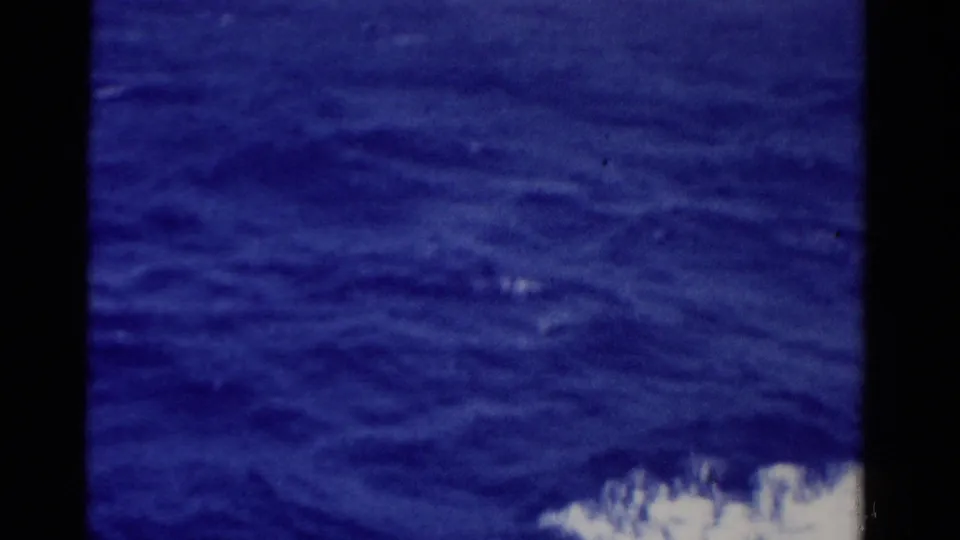 1975 Florida 8mm frame showing deep blue open sea, rippled water, and a small band of white foam at the bottom edge.