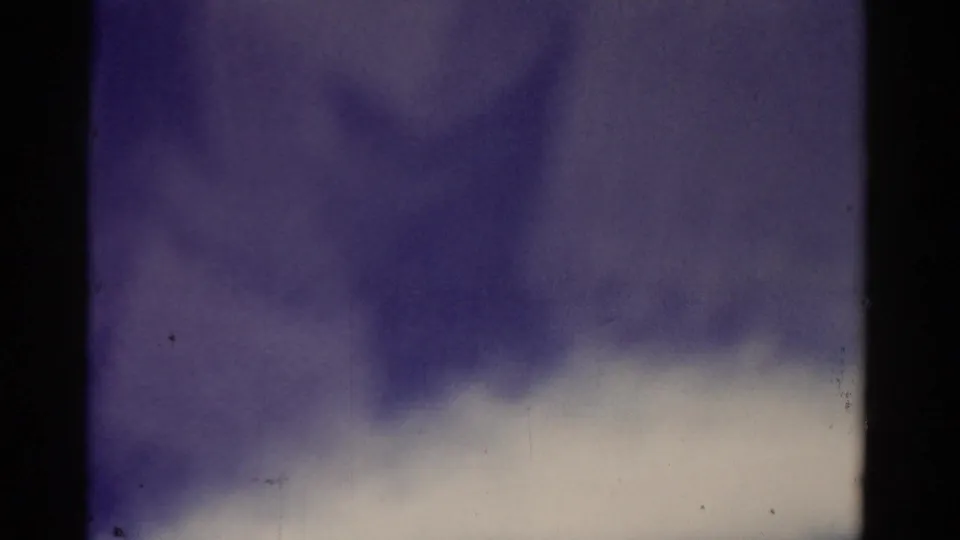 1975 Florida 8mm frame where the sea view is obscured by a soft, out-of-focus foreground shape and muted blue tones.