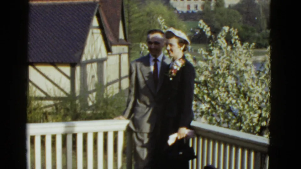 A 1975 Boston balcony portrait shows the couple closer to center frame, partly shaded against flowering trees and a half-timbered structure.