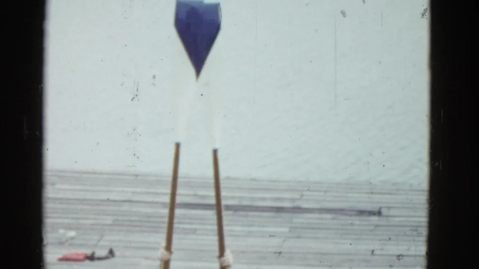 The frame shows the lower portion of the poles and support area on the dock, with the performer mostly cropped out above.