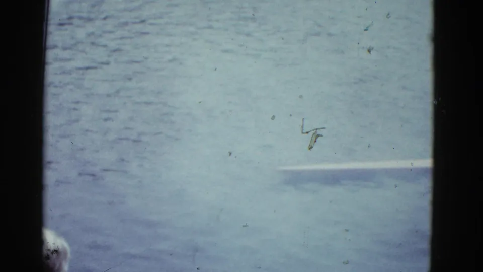 Open river water fills the frame, with a faint pale horizontal object or shoreline detail at right.