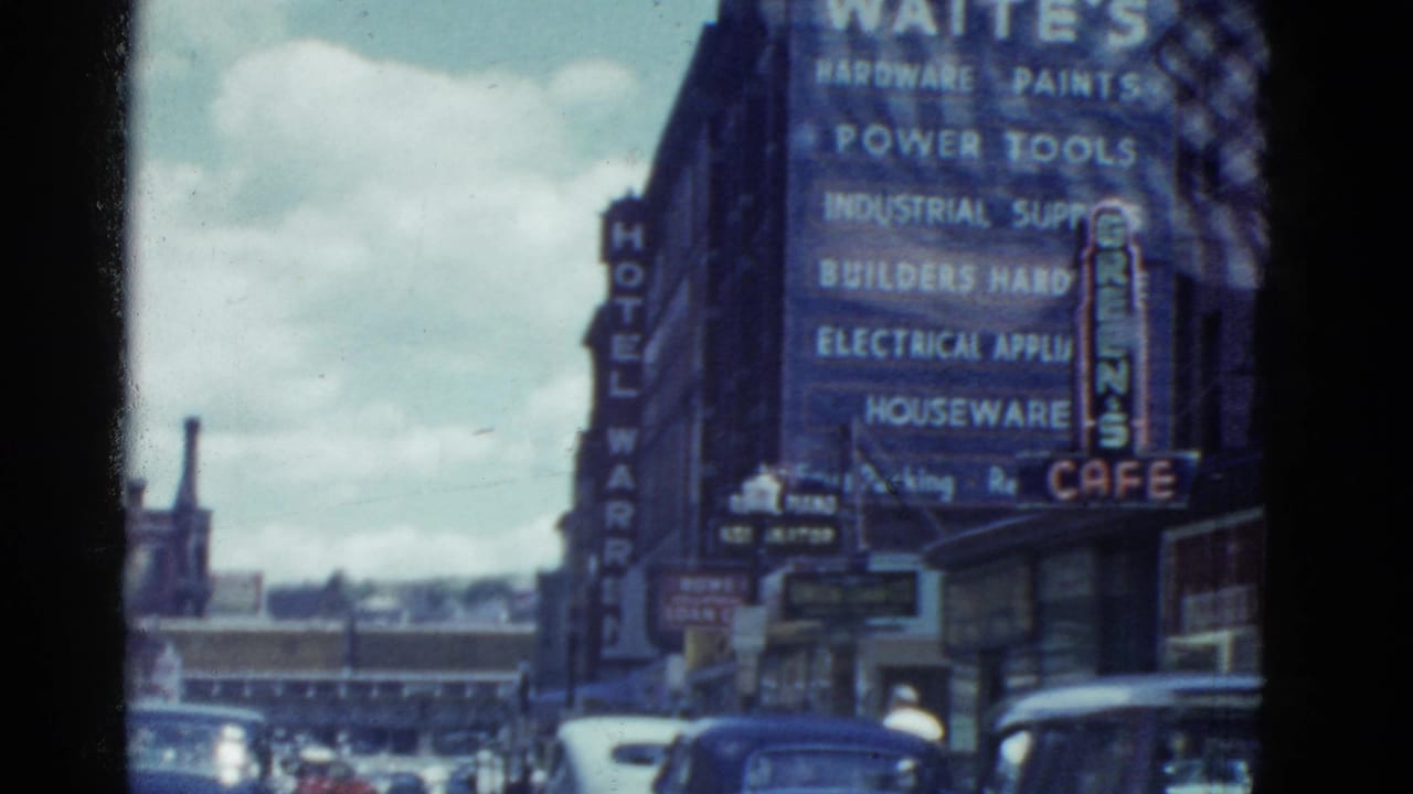 Boston street with Waites Hardware sign, Hotel Warren sign, cars, and storefronts.