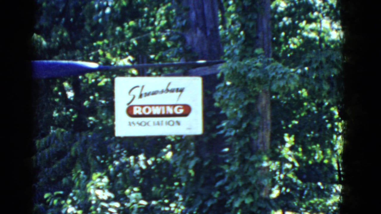 1975 8mm view of the Shrewsbury Rowing Association sign surrounded by leafy woods, with the oar partly in frame.