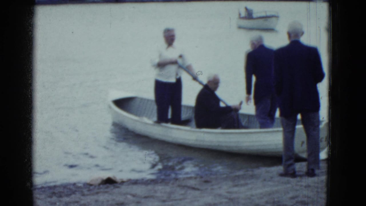 Several men gather around a small white rowboat near shore.