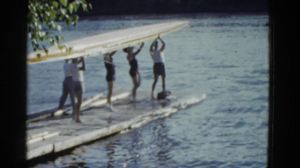 In the final frame, young men lift the long rowing shell overhead on the dock, with calm water and tree leaves in the background.