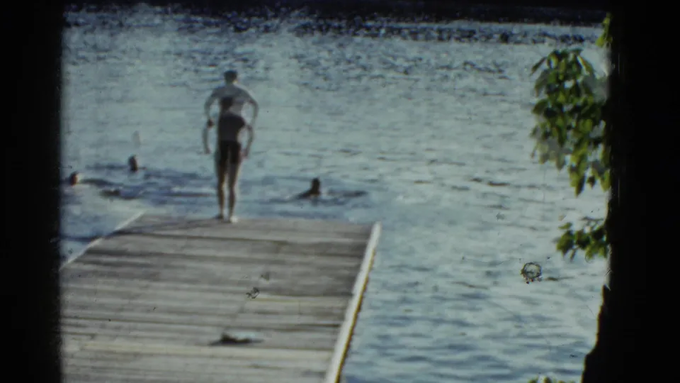A final lakeside frame shows a man at the dock edge with swimmers in the water, framed by leaves and dark 8mm borders.