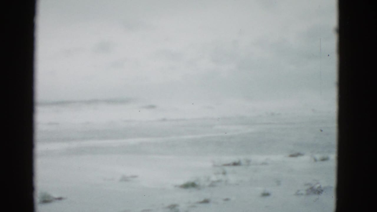 1975 Boston-area 8mm frame showing a frozen lake, low horizon, and overcast winter sky with visible film-gate edges.