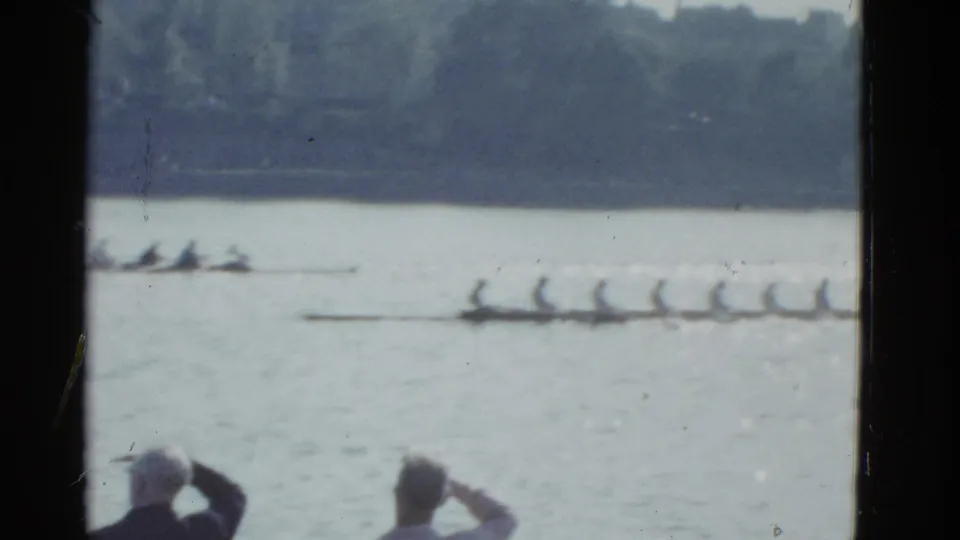 Two racing shells are visible on the river with spectators in the foreground, consistent with 1975 Boston home-movie rowing footage.
