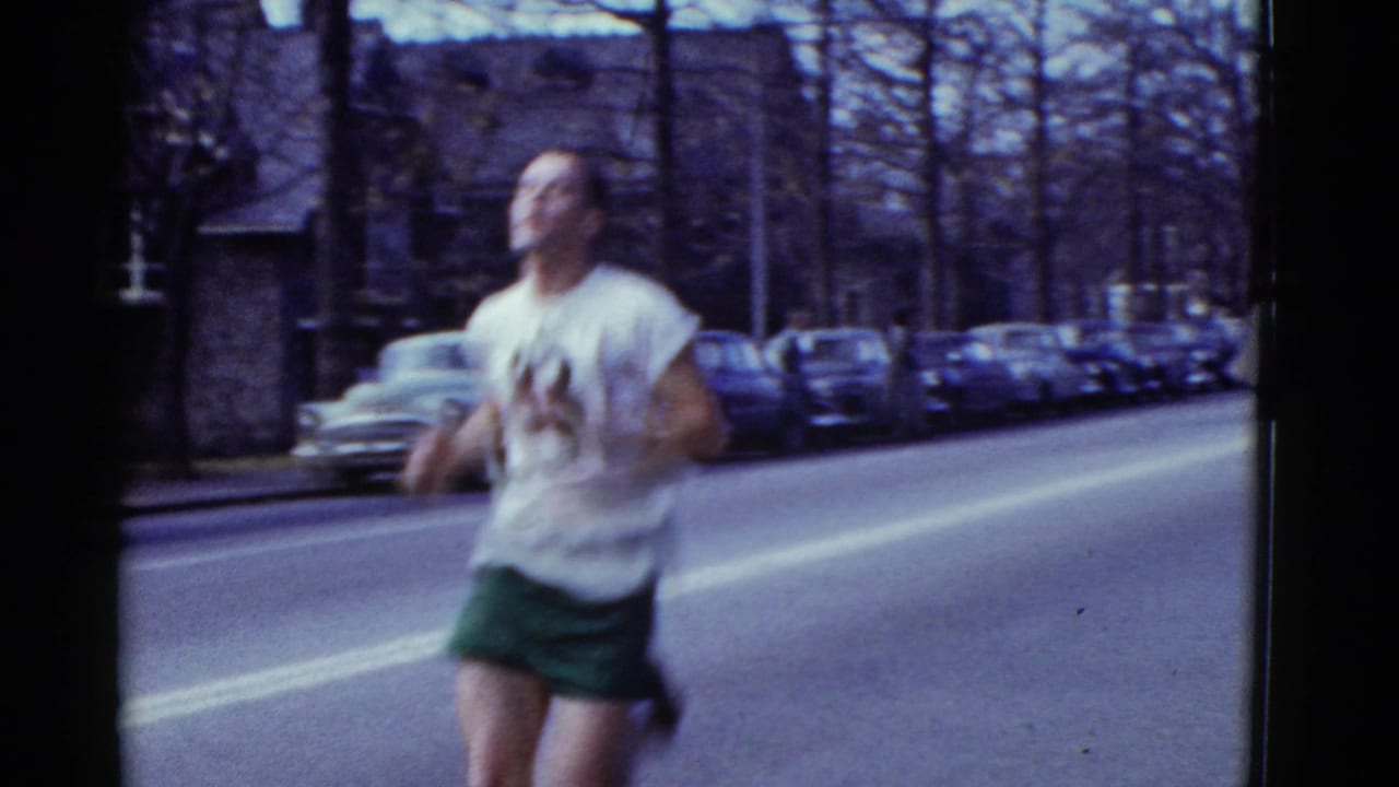 Runner passes close to the camera in motion blur on a tree-lined city street.
