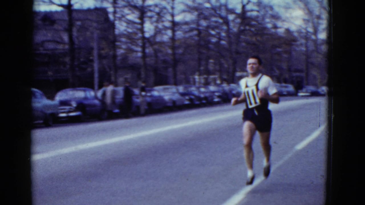 A male runner in a black-and-white bib 11 outfit passes close to the camera during the 1975 Boston road race.