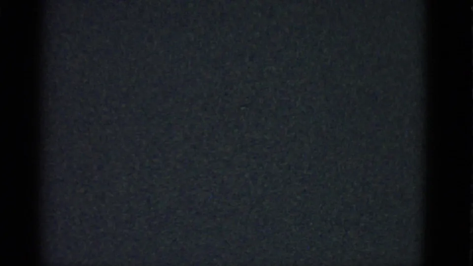 Grainy 8mm frame from the 1975 clip showing mostly black static with faint vertical tonal bands.