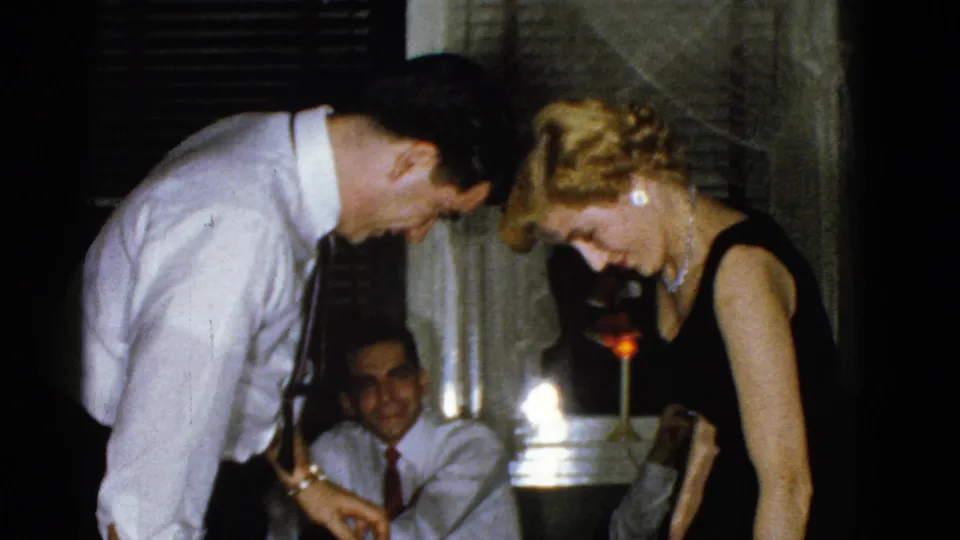 The man and woman lean their heads close together while another guest sits behind them in the 1975 Boston interior.