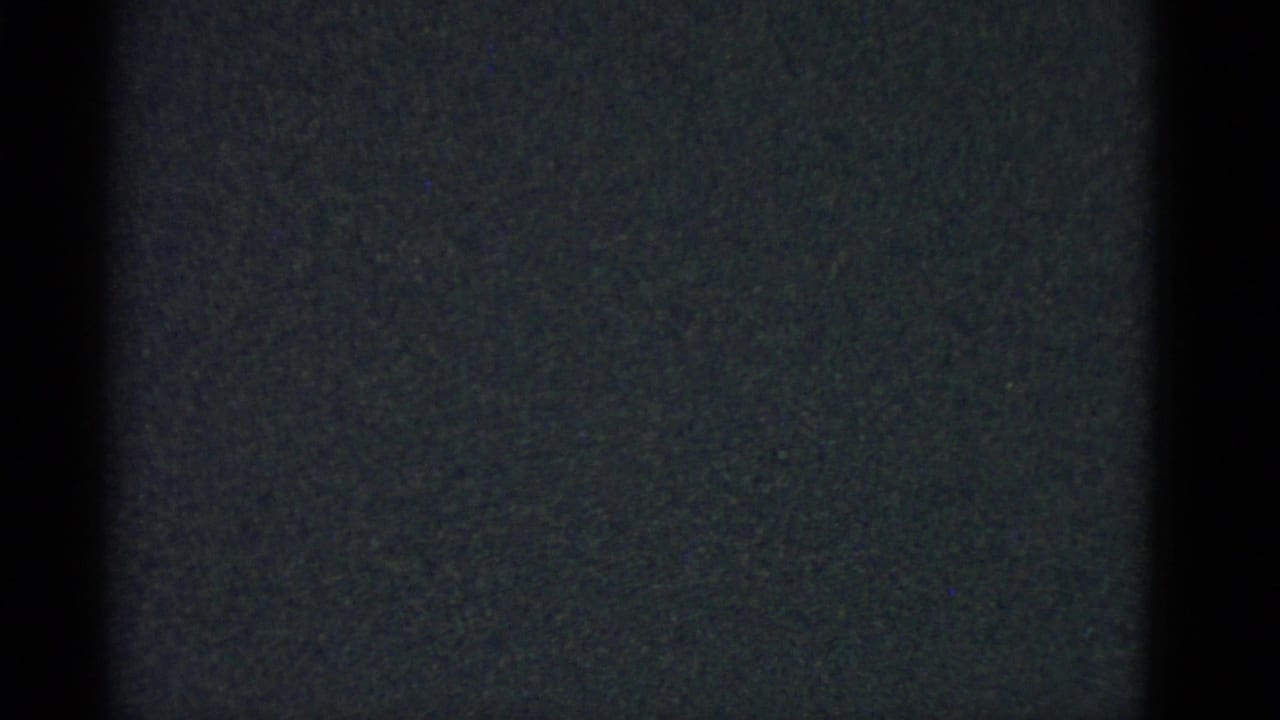 Underexposed 8mm frame with dark borders and visible film grain from the Boston home-movie clip.