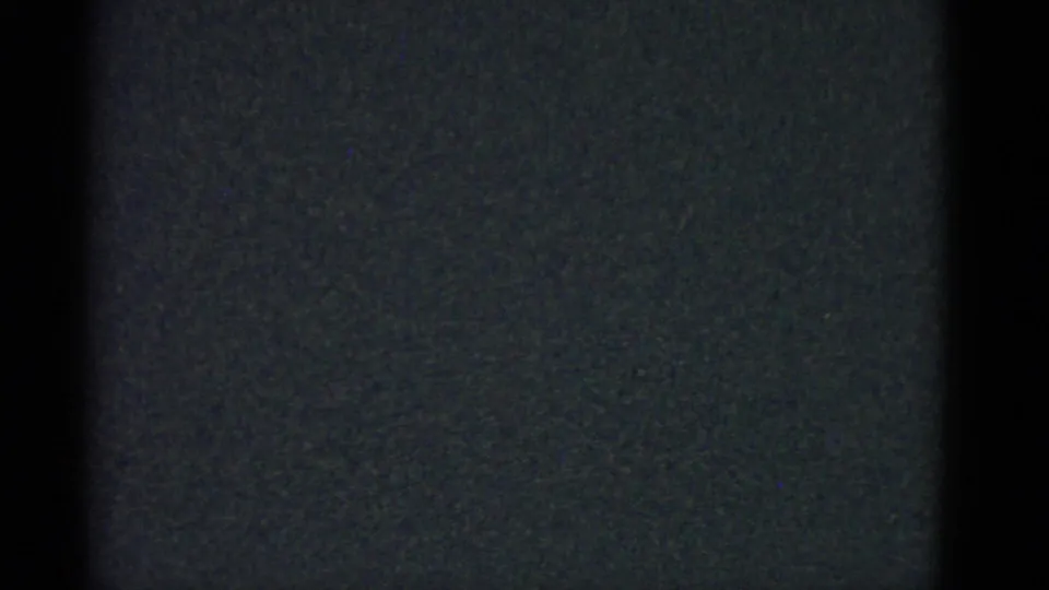 Underexposed 8mm frame with dark borders and visible film grain from the Boston home-movie clip.