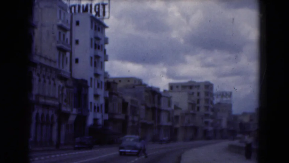 1975 Florida street view from a vehicle, showing mid-century buildings, cars on the road, sidewalks, signage, and an overcast sky.