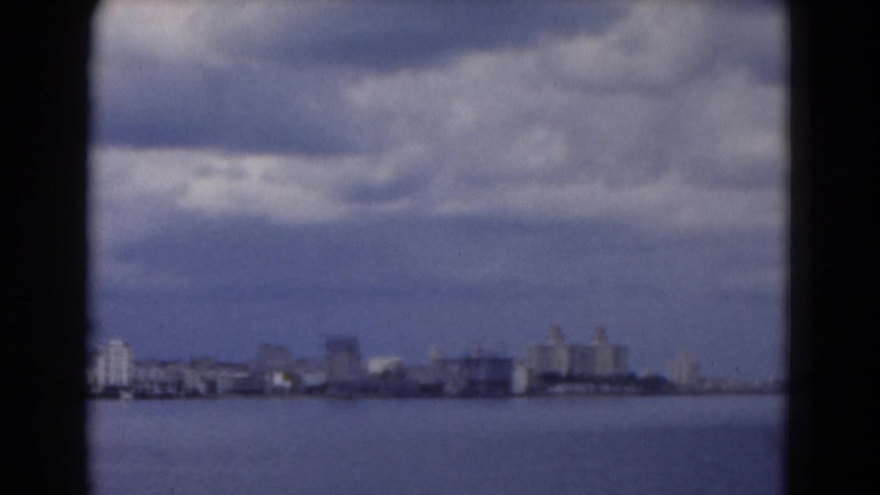 Distant shoreline buildings across water with clouds overhead.
