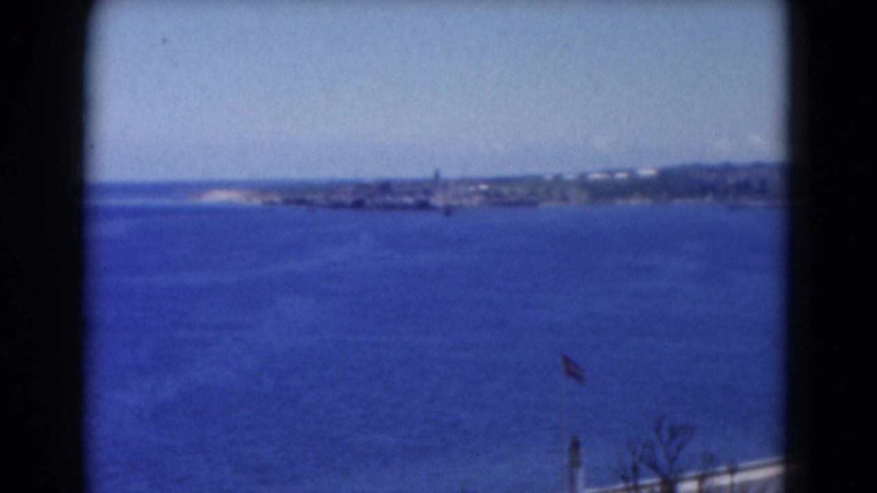 Blue ocean with a distant shoreline seen through dark film-frame edges.