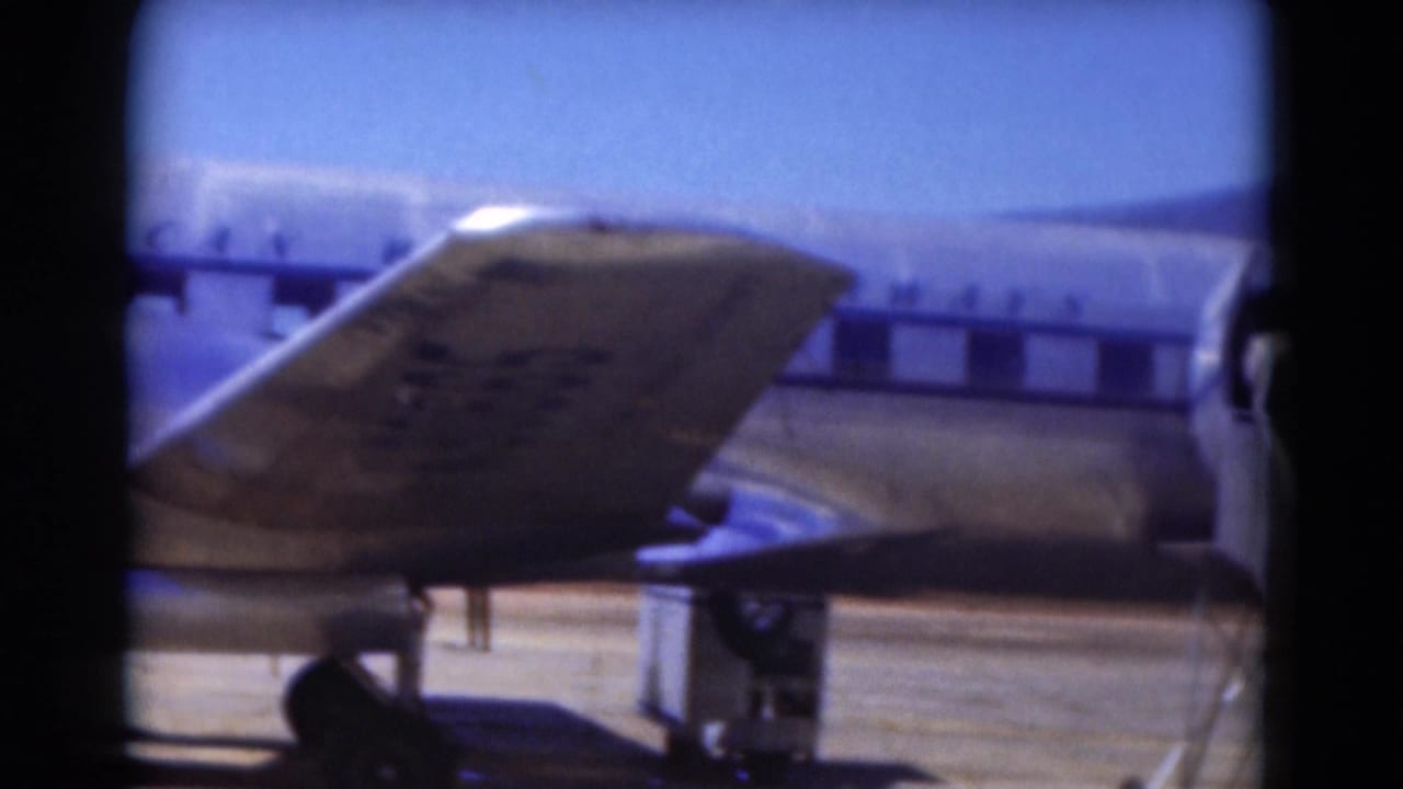 Tail and rear fuselage of a silver airplane with stairs near the cabin door.