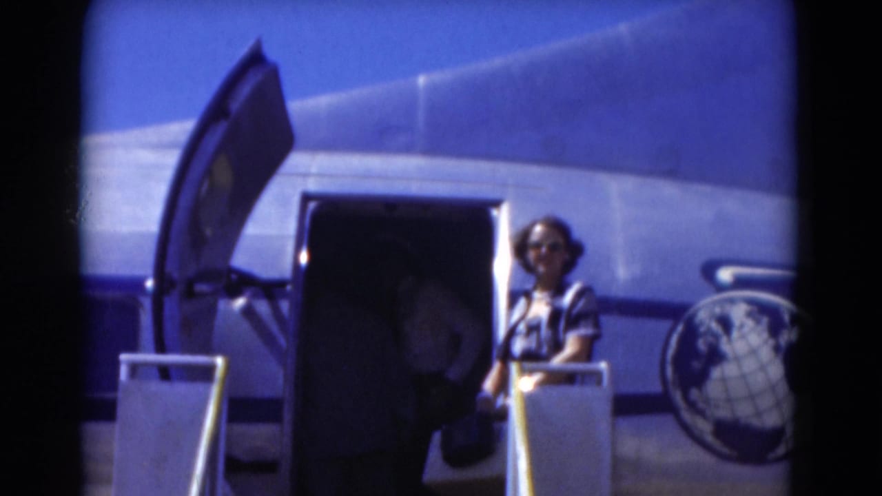 Open aircraft door with a woman standing by the stairs and a globe logo on the fuselage.