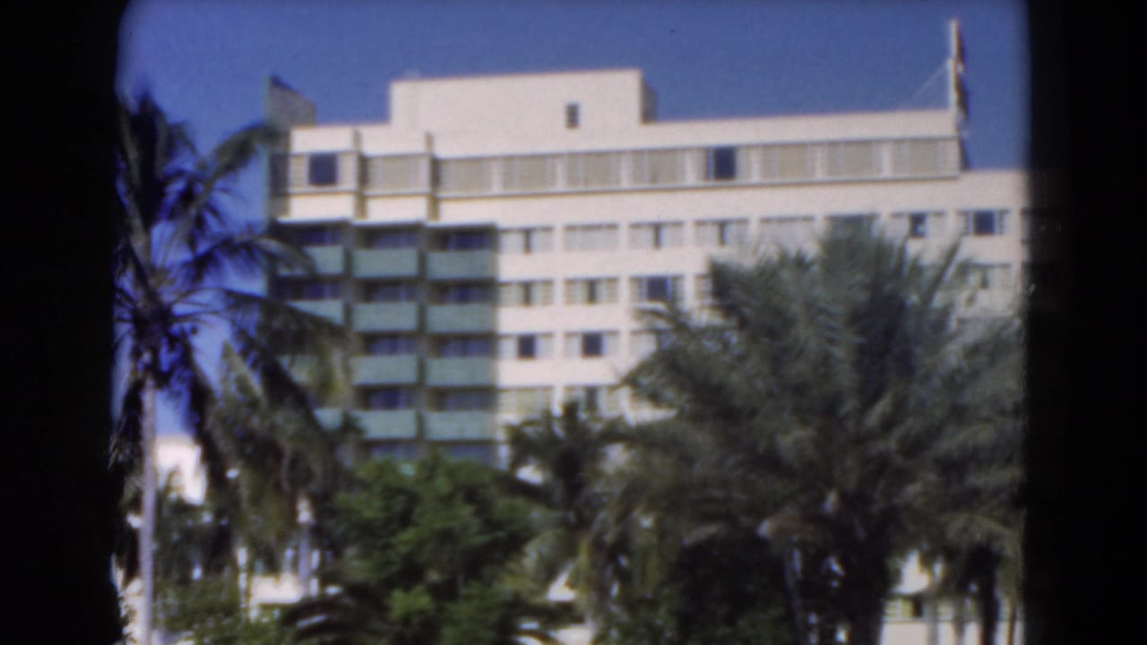 White Florida building with stacked balconies and palms, filmed on 8mm with soft focus and saturated sky.
